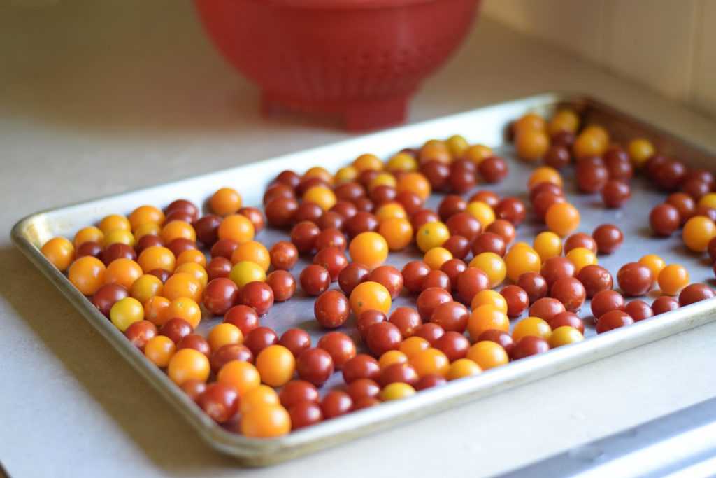 Orange and red cherry tomatoes on a sheet pan.