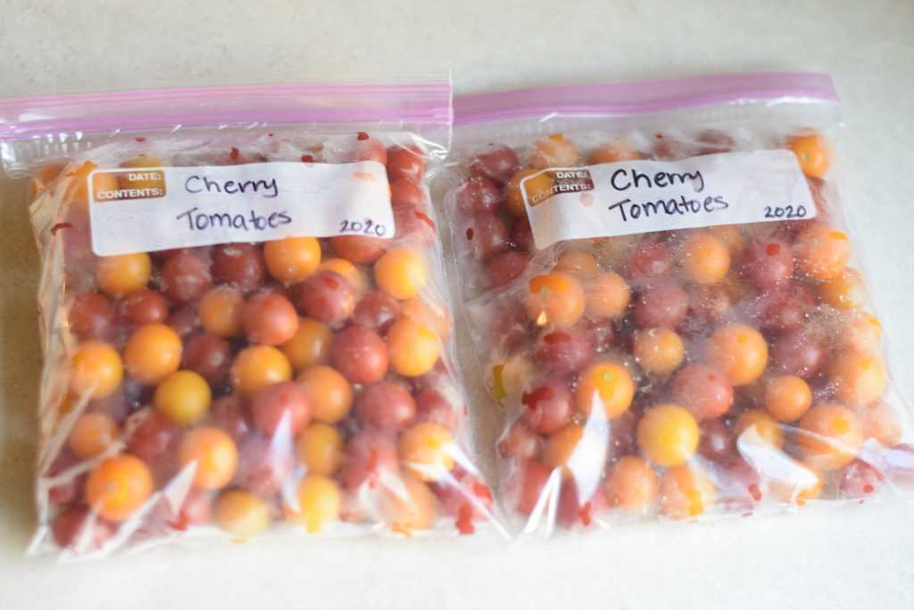 Two bags of orange and red cherry tomatoes.
