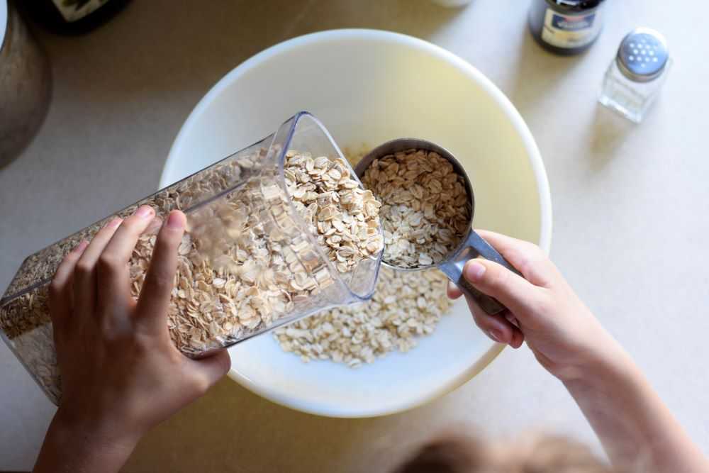 Pouring oats into a measuring cup over a bowl