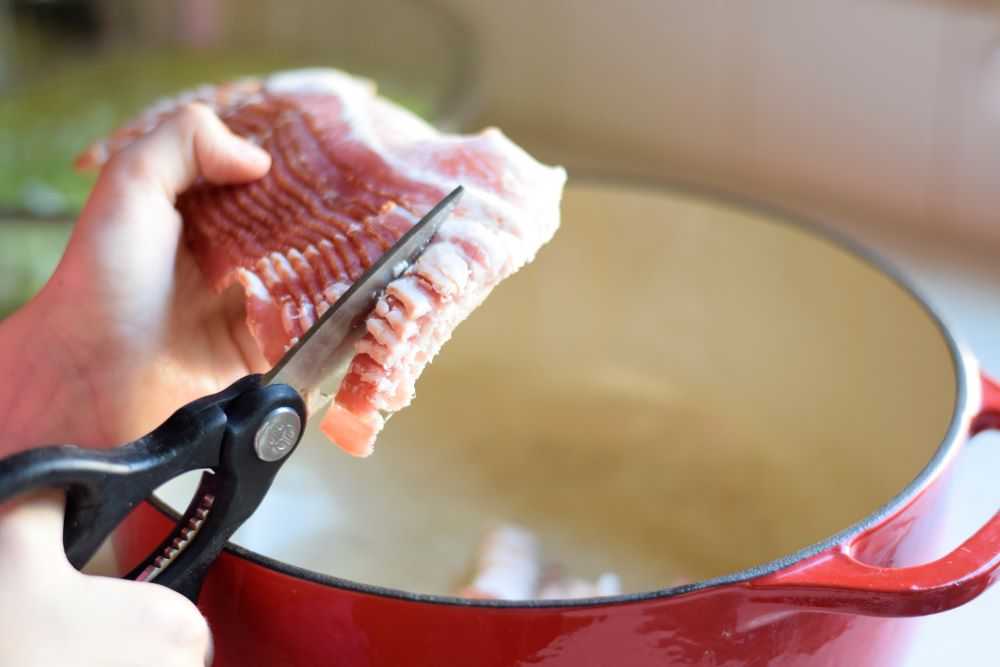 cutting bacon into a pan