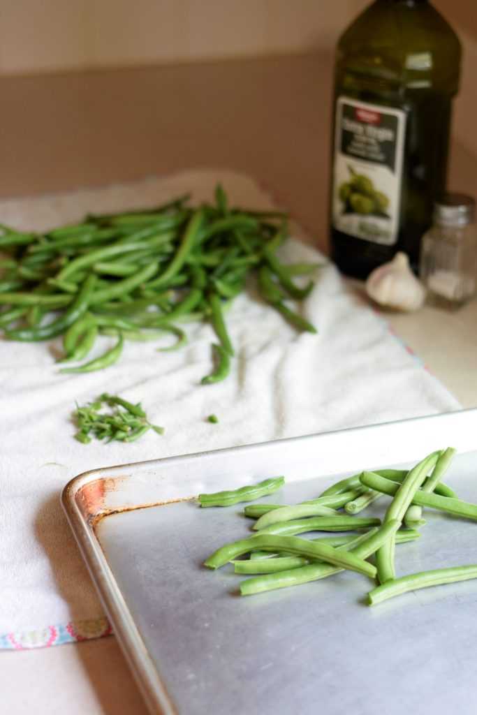 Snapping green beans onto a sheet pan.
