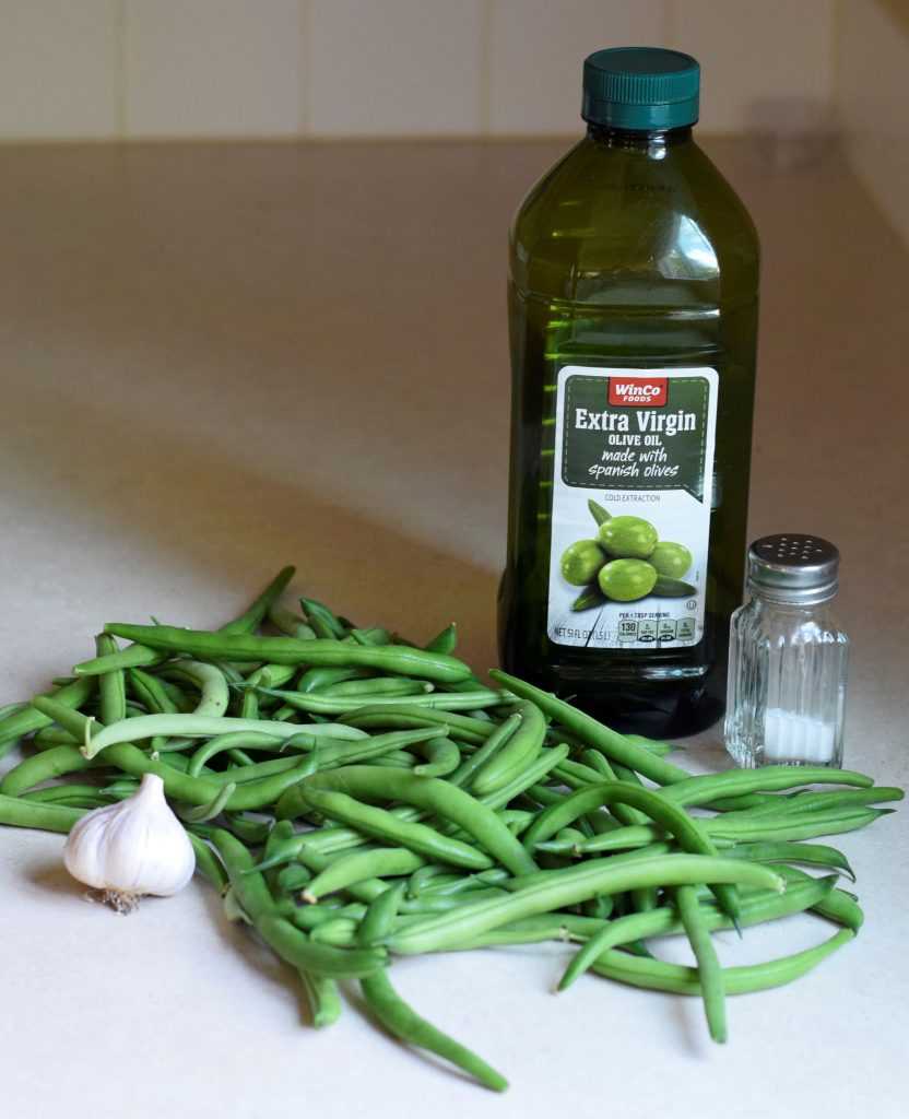 Green beans, garlic, salt, and oil on the counter.