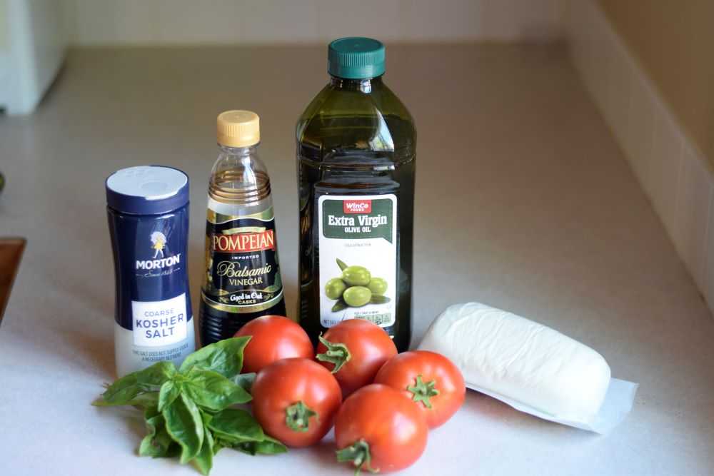 Ingredients for caprese salad: tomatoes, basil, and mozzarella cheese.