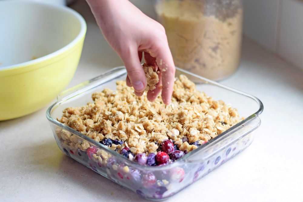 Sprinkling the topping on cranberry blueberry crisp